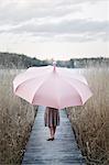 Woman with umbrella standing on wooden pier