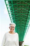 Portrait of senior woman standing under green bridge
