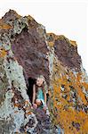 A young girl looking out of a hole in the rocks