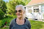 Senior woman in sunglasses in front of house