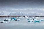 Ice floe on Jokulsarlon lake with snowcapped mountain range on horizon