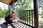 Mature woman painting porch railing