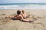 Boy and girl in hole in sand on beach in Santa Barbara