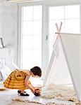 Girl playing next to tent at home