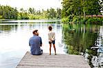 Father and daughter on pier beside lake in Friseboda, Sweden