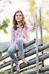 Portrait of smiling girl sitting on fence