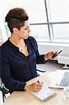 Woman making notes during board meeting