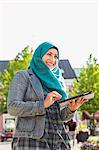 Muslim woman using tablet and smiling