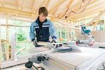 Mid adult man cutting wood with electric saw