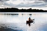 Man paddling canoe on lake