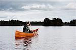 Mature man in boat on lake with forest on horizon