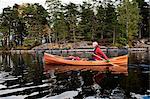 Mature man in boat on lake with forest on shore