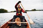 Mature man and dog in boat on lake