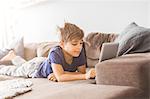 Boy on sofa playing with tablet PC