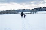 Rear view of mother and child walking in snow