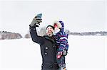 Father taking selfie with son in snow