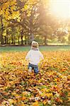Little boy playing in autumn leaves in Sweden