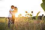 Couple embracing in field at sunset