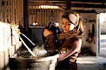 Woman pouring water from watering can to bucket