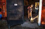 Woman sweeping in barn