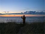 Man photographing moody sky over lake