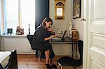 Woman in black dress using laptop at home