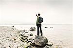 Woman holding up phone on rocky coastline of Sodermanland, Sweden