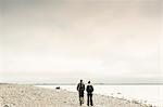 Rear view of couple walking along rocky coastline in Stockholm, Sweden