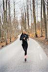 Young woman running on rural road in Sodermanland, Sweden