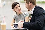 Young businessman and woman having discussion at sidewalk cafe