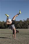 Women on football pitch doing handstand with football