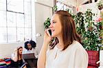 Woman in office making telephone call on smartphone