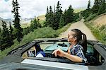 Young woman looking out from four wheel convertible in Rocky mountains, Breckenridge, Colorado, USA