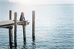 Woman sitting on pier looking away