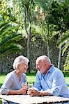 Senior couple sitting in garden, enjoying glass of wine