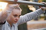 Young woman training, leaning against handrail in park