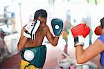 Mature woman practicing boxing with male trainer in gym