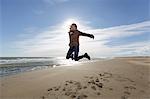 Young woman jumping mid air on beach, Tarragona, Catalonia, Spain