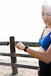 Young woman training on sea waterfront, looking at smartwatch