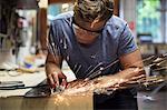 Man in workshop, making ski equipment, using hand tools on metal