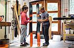 Man and woman in workshop, inspecting ski equipment