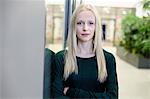 Portrait of young businesswoman with arms folded at office entrance