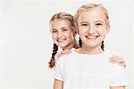 Studio portrait of two smiling girls, head and shoulders