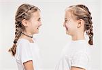 Studio portrait of two girls with hair plaits face to face, head and shoulders