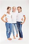 Studio portrait of three girls posing with hands on hips