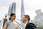 Young businessman and woman moving up escalator in Shanghai financial centre, Shanghai, China