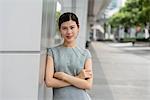 Portrait of young businesswoman leaning against wall in city, Shanghai, China