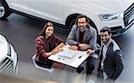 Portrait smiling car sales people meeting in car dealership showroom