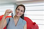 Portrait smiling, enthusiastic female customer holding car keys in car dealership