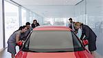 Customers looking at new car in car dealership showroom